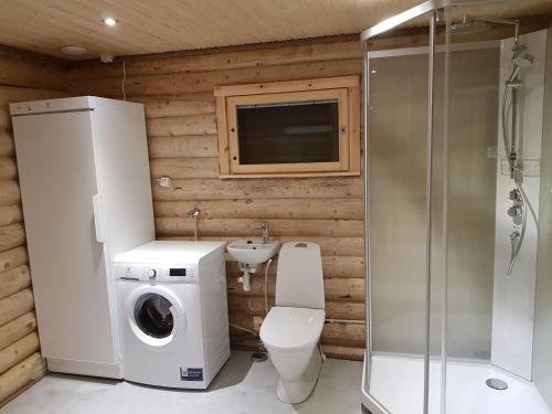 a bathroom with a toilet and a sink and a washing machine at Tunturihuvila III in Vuontisjärvi