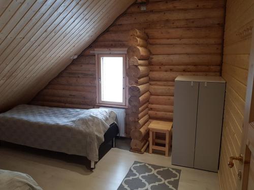 1 dormitorio en una cabaña de madera con cama y ventana en Tunturihuvila III, en Vuontisjärvi