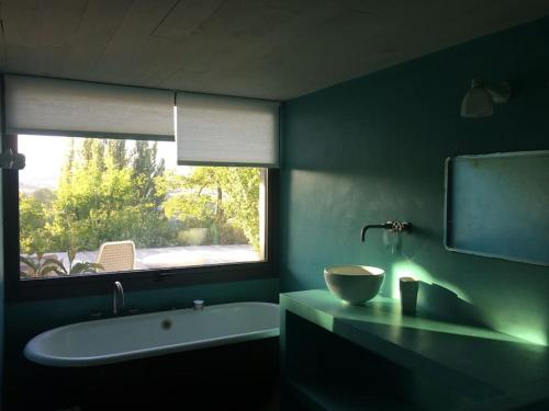 een badkamer met een bad, een wastafel en een raam bij MAISON CALME ET LUMINEUSE OUVERTE SUR LA NATURE in Truinas