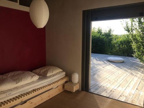 een slaapkamer met een bed en een grote glazen schuifdeur bij MAISON CALME ET LUMINEUSE OUVERTE SUR LA NATURE in Truinas