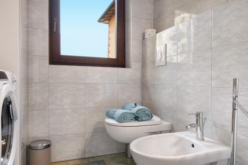 a bathroom with a toilet and a sink and a window at Fogazzaro Lake View Apartment in Oria