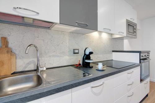 eine Küche mit weißen Schränken und einem Waschbecken in der Unterkunft Fogazzaro Lake View Apartment in Oria