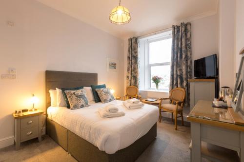 a bedroom with a bed with a desk and a window at Sure Hotel Collection by Best Western Porth Veor Manor Hotel in Newquay
