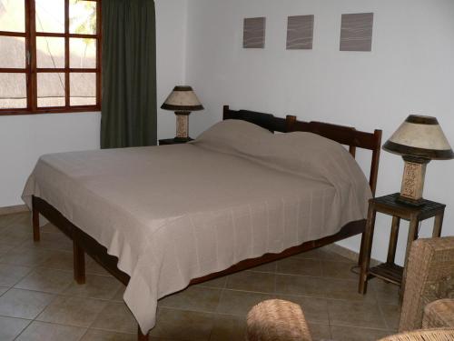 a bed in a bedroom with two lamps on tables at Blue Moon Beach Holiday Resort in Inhambane