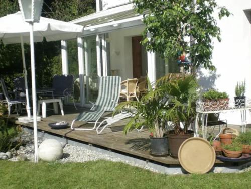 um pátio com cadeiras e vasos de plantas e um guarda-sol em Sonnenloft Else und Studio Luise em Neubeuern