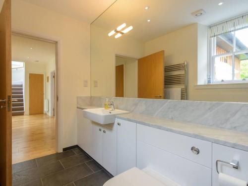 a white bathroom with a sink and a mirror at Fidra Cottage in Dirleton