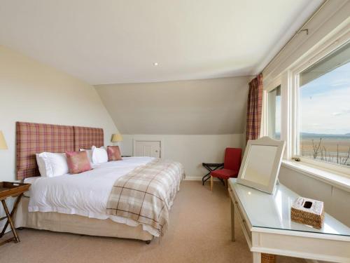 a bedroom with a bed and a desk and a window at Green Craig in Aberlady