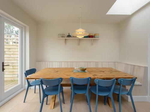 a dining room with a wooden table and blue chairs at Marine House in Gullane