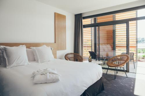 a bedroom with a large white bed and a balcony at Hôtel & Spa Villa Seren in Hossegor