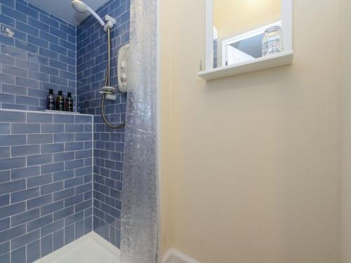 a bathroom with a shower with blue tiles at Kittiwake in North Berwick