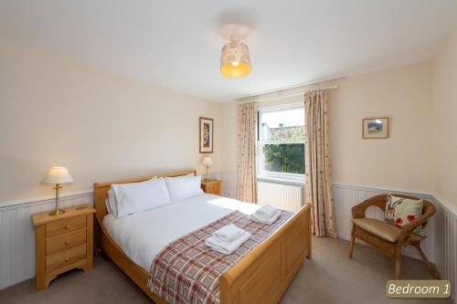 a bedroom with a bed and a chair and a window at Hideaway Cottage in Dirleton