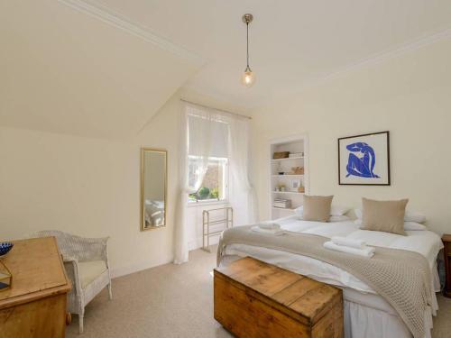 a white bedroom with a large bed and a table at Forthview in North Berwick