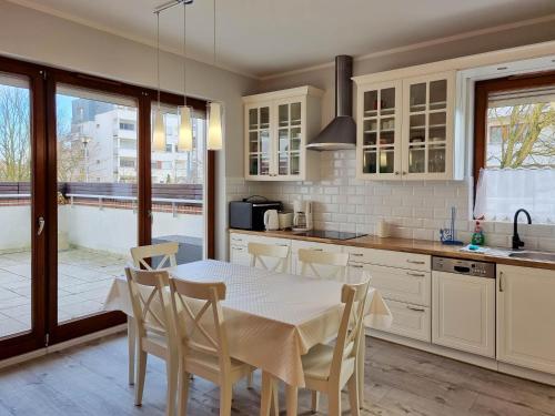 eine Küche mit einem Tisch und Stühlen sowie eine Küche mit weißen Schränken in der Unterkunft visit baltic - na Platanie in Świnoujście