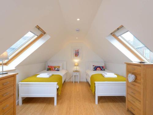 2 Betten in einem Dachzimmer mit 2 Fenstern in der Unterkunft Curlew in North Berwick