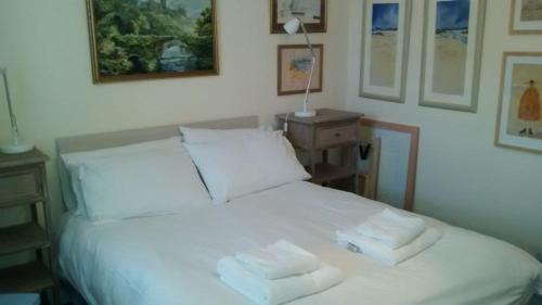 a bedroom with a white bed with two towels on it at Harbourside Cottage in North Berwick