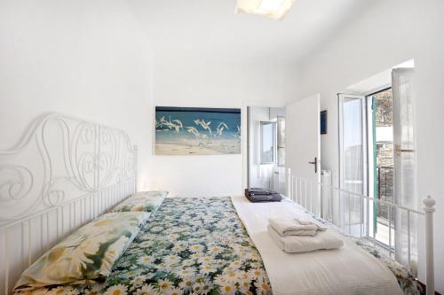 a white bedroom with a bed with a floral bedspread at The Family Free Parking in Alassio in Alassio