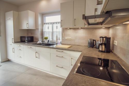 a large kitchen with white cabinets and a sink at Ferienhaus Rena in Krummhörn
