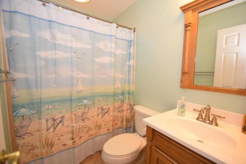 a bathroom with a shower curtain with a toilet and a sink at Harbour Island 21C townhouse in Ocean City