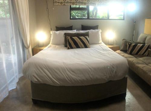 - une chambre avec un grand lit et un canapé dans l'établissement Gecko Cottages, à Hectorspruit