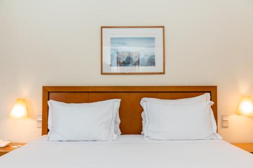 a bed with two white pillows and a picture on the wall at Hotel Roma in Lisbon