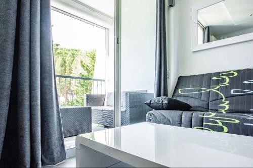 un salon avec un canapé et une fenêtre dans l'établissement Bleu soleil * Clim * Parking privé * Chambre * Terrasse, à La Grande Motte