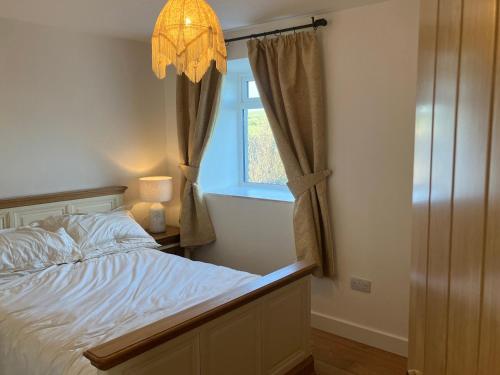 - une chambre avec un lit, une fenêtre et un lustre dans l'établissement Cherry Tree Cottage, à Stranraer