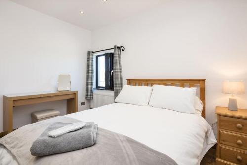 a bedroom with a white bed with a pillow on it at NEW BARN CONVERSION WITH PRIVATE HOT TUB in Halifax