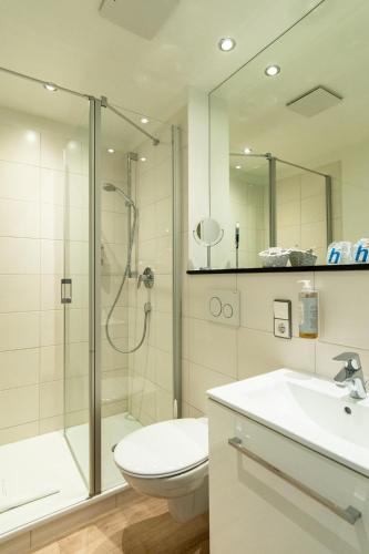 a bathroom with a shower and a toilet and a sink at Hotel am Fischerstrand in Bansin