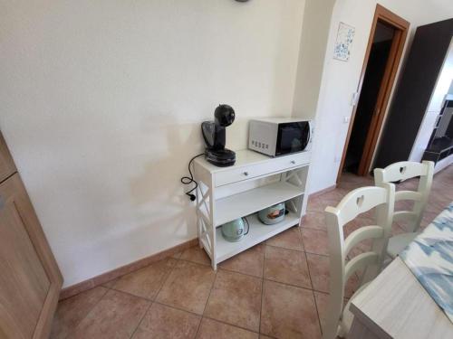 a small white cabinet with a microwave and a television at Casa Boi Dessena 1 in Orosei