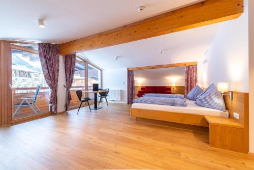 a bedroom with a bed and a desk in a room at Pension Haus in der Sonne in Fieberbrunn