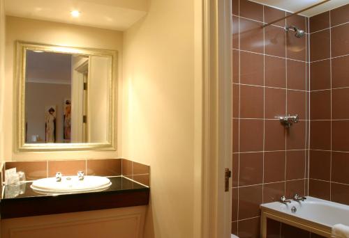 ein Bad mit einem Waschbecken und einem Spiegel in der Unterkunft The Greyhound Hotel in Leigh