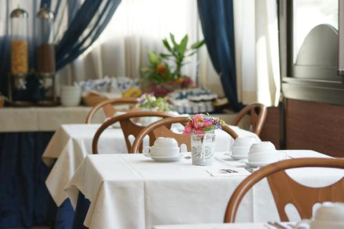 un comedor con mesas blancas y sillas con flores en Hotel Verudella, en Rímini