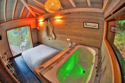 聖讓多普斯的住宿－Chalet dans les Arbres，一间带浴缸的浴室和一张位于客房内的床