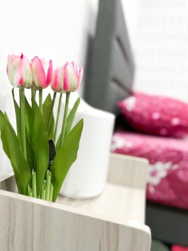 a group of pink flowers in a vase on a table at Mekming Lodging - Homestay in Melaka