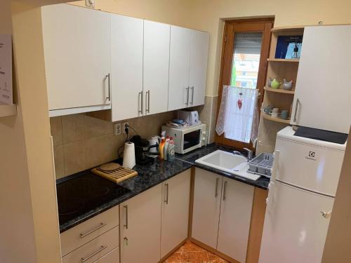 a kitchen with white cabinets and a white refrigerator at Bíbor Apartman in Gyula