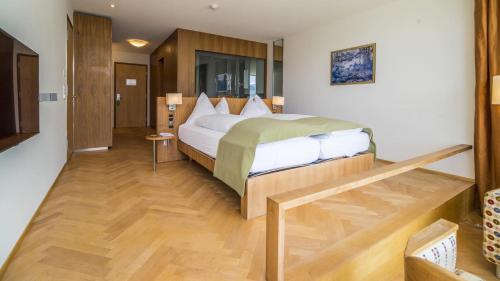ein Schlafzimmer mit einem großen Bett und Holzboden in der Unterkunft Waldhotel & SPA Davos - for body & soul in Davos