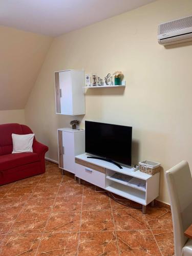 a living room with a tv and a red couch at Bíbor Apartman in Gyula