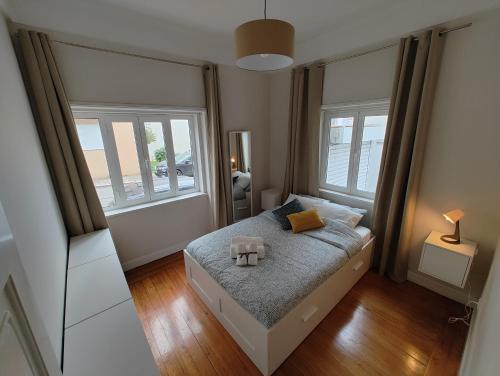um pequeno quarto com uma cama e 2 janelas em Casa Veríssimo no Porto