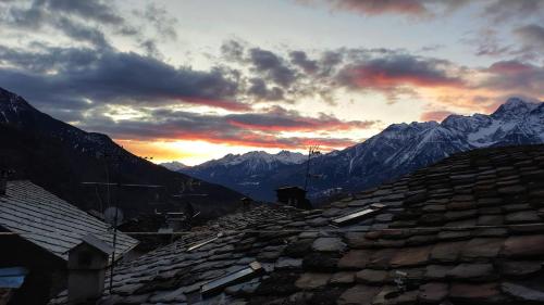 una puesta de sol sobre los tejados de un pueblo con montañas en Meizon - La Montagna, Pila, Crevacol, Aosta e Valpelline, en Gignod