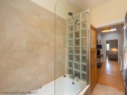 uma casa de banho com uma banheira e um chuveiro em vidro. em Rosebery Place em Gullane