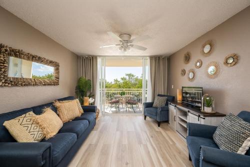 ein Wohnzimmer mit einem blauen Sofa und einem TV in der Unterkunft Comfy 2/2 condo with pool/gym/tennis/hot-tub in Key West