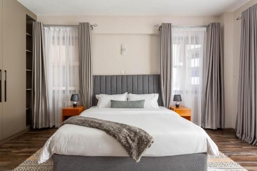una camera da letto con un grande letto bianco e finestre di Mizuki a Nairobi