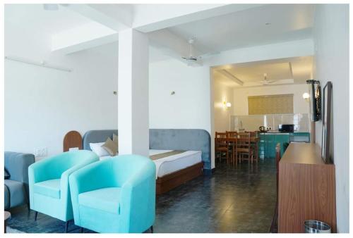 a bedroom with blue chairs and a bed and a kitchen at The Periwinkle Homestay Bhimtal in Bhīm Tāl