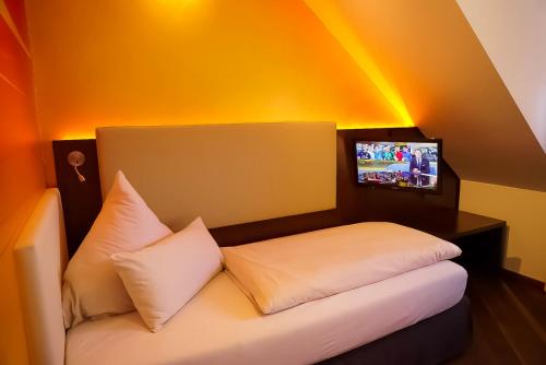 a room with a bed with a tv on the wall at Hotel Deutsche Eiche in Munich
