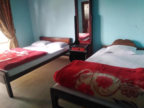 a bedroom with two beds with red sheets and a mirror at Access Villa in Nuwara Eliya
