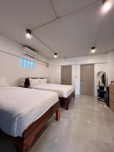 a bedroom with two beds and a desk in it at Naisang Hostel in Chumphon