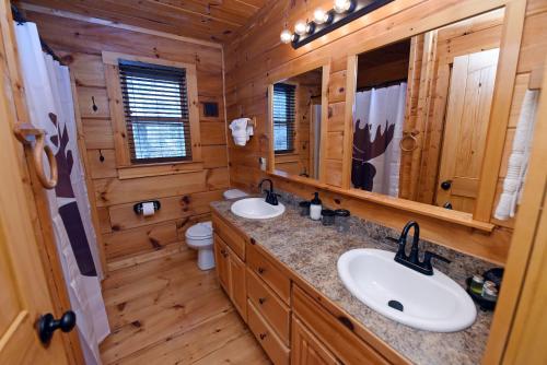 a bathroom with two sinks and mirrors in a log cabin at Bucking Bison - Pet friendly, mountain view, hot tub, game room, fire pit and more! in Mineral Bluff