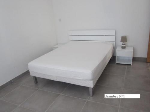 une chambre avec un lit blanc et une table de chevet dans l'établissement Location paisible entre mer et collines - Bormes Les Mimosas, à Bormes-les-Mimosas