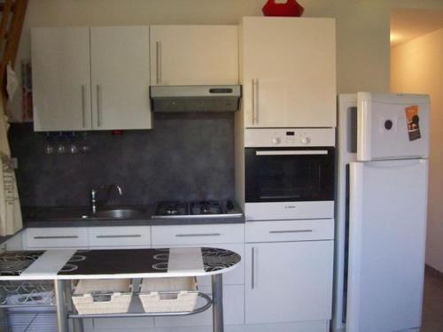 uma cozinha com armários brancos e um frigorífico branco em vacances de charme et au calme ;) em Bormes-les-Mimosas