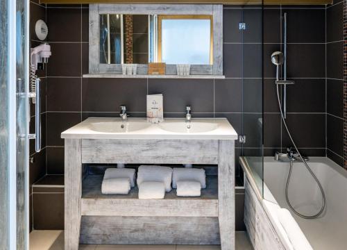 a bathroom with a sink and a mirror and a tub at Hôtel L'Aiguille Percée in Tignes